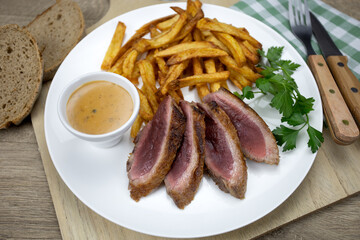 magret de canard grillé et frites dans une assiette