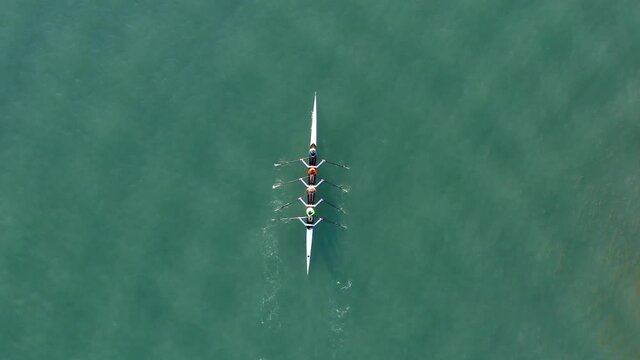Sport Canoe with a team of four people rowing on tranquil water, Aerial view.