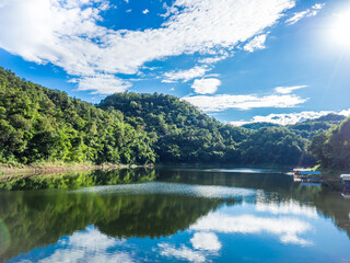 Reservoirs in completely natural source surrounded by mountains and trees on the day when the sky is clear blue with beautiful clouds.