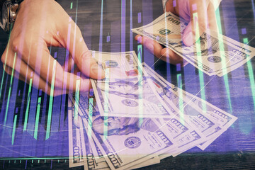 Multi exposure of financial graph drawing hologram and USA dollars bills and man hands. Analysis concept.