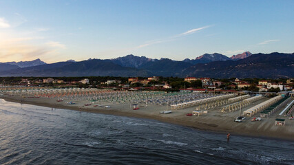 Sunset aerial view from drone over sandy beach with sea waves and mountains in background and copy space for text 