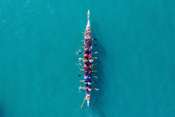 Dragon Boat team rowing to the pace of an onboard Drummer, Aerial view.