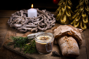 Homemade liver pate in glass jars on rustic festive/christmas table with sourdough bread