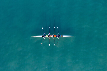 Sport Canoe with a team of four people rowing on tranquil water, Aerial view. - obrazy, fototapety, plakaty