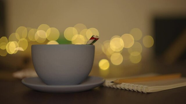 blue cup with hot cholate on table with christmas lights on background in dark evening light