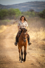 Brunette smiles riding horse along dirt track