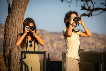 Brunettes using camera and binoculars in jeep