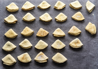 homemade cookies in the form of triangles before baking. Homemade cakes on a baking sheet.