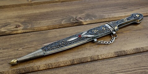 Dagger with ornate pattern on wooden background
