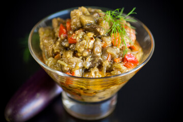 cooked summer eggplant caviar with vegetables in a bowl on black background