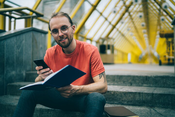 Handsome guy surfing phone reading notebook in pedestrian bridge