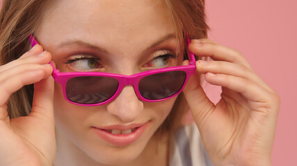 Portrait of young caucasian woman looking over the pink sunglasses. High quality photo
