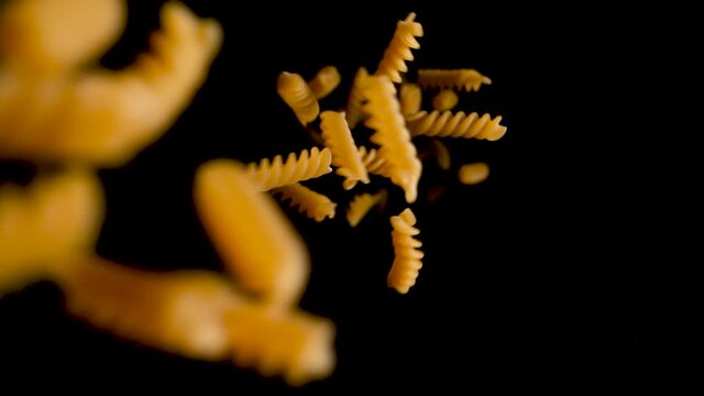 Curly Corkscrew Italian Pasta Noodles Falling into Black Background