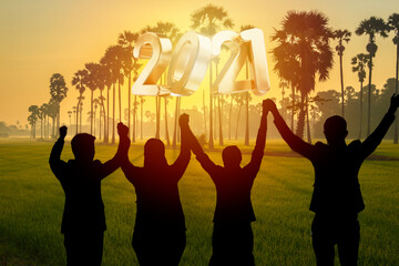 Happy new year 2021, Silhouette of 2021 letters on the mountain with business people raised arms in teamwork concept at sunrise.