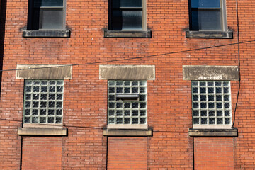 Red brick old commercial industrial building, lower windows with glass brick, architectural details, horizontal aspect