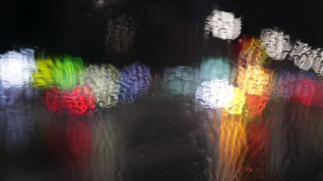 Night city traffic in the rain. Car lights through wet glass. Abstract shot of evening city traffic bokeh