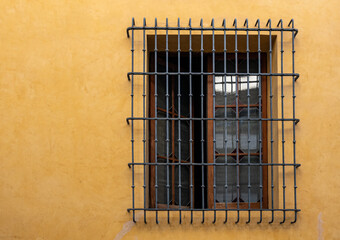 Big window with iron grill, in a yellow wall
