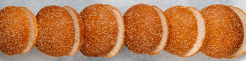 Delicious homemade fresh sesame buns cut in half for burgers close-up. Top view, selective focus