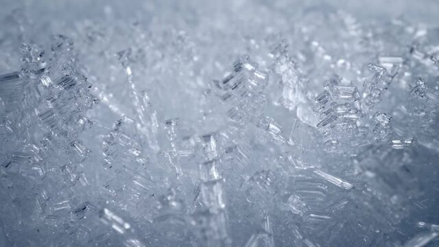Super macro sliding shot of snow crystal, snowflakes. Camera moves through bizarre frozen flakes of snow. Ice formations, frost. Winter nature background. UHD