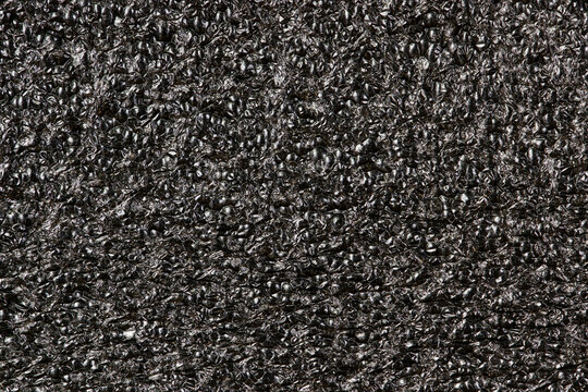 Black Expanded polyethylene foam sample background. EPE beads packing material with macro details, textures and one solid color.