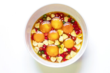 Pickled eggs yolk in fish sauce with chili pepper and garlic sliced in white bowl isolated on white background.
