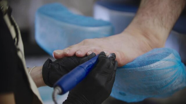 Pedicure procedure - the master grinding the toenails of her male client