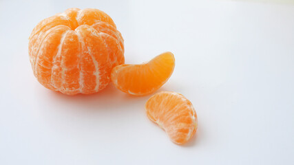 Peeled whole tangerine and two tangerine slices isolated on white background. Vitamins. Place for your text. Selective focus.