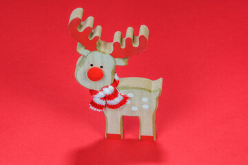 Advent Feast festive Christmas wooden decoration with reindeer. Seasonal colorful miniature figure before red background.