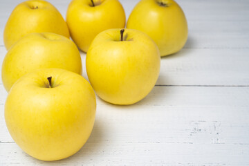 Beautiful yellow ripe Golden apples on white wooden table. Sweet and juicy fruits.