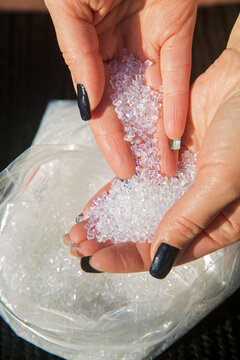 white keratin granules in a woman's hands are used to encapsulate strands of hair. 