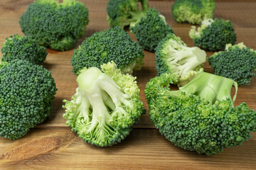 Pieces of fresh green broccoli on wooden table.