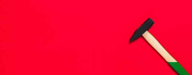 Hammer is isolated on a red background with place for text. Shop banner with construction tools. New Year or Christmas festive backdrop. One of the basic home use instrument for hammering nails