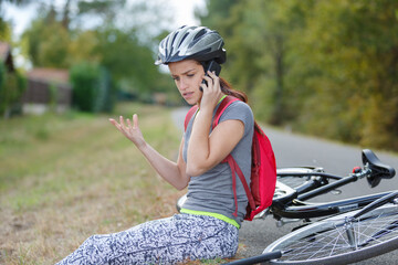 woman with bicycle puncture gesticulating while using phone