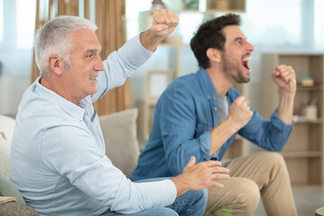 excited man and father on couch watching football game