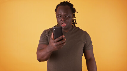 Shocked african american black man looking at the screen of his phone. Unexpected text message or...