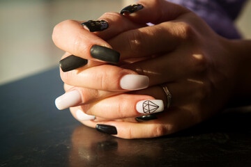 women's hands close-up with black and white manicure, Sunny photo.