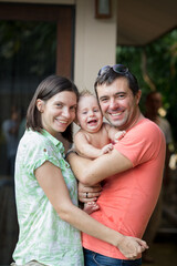 Naklejka premium Beautiful young family laughing and hugging with their little son
