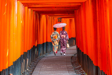 Fototapeta premium Women in traditional japanese kimonos walking at Fushimi Inari Shrine in Kyoto, Japan