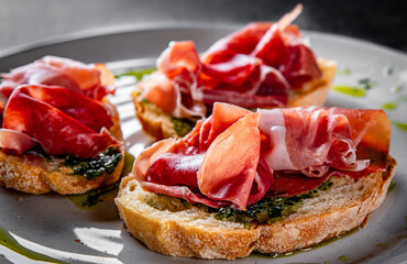 Bruschetta with prosciutto and pesto sauce on plate