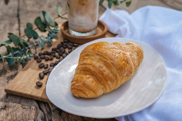 Croissant in a white plate placed on a wooden table.