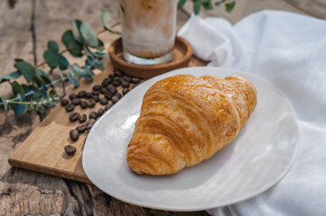 Croissant in a white plate placed on a wooden table.