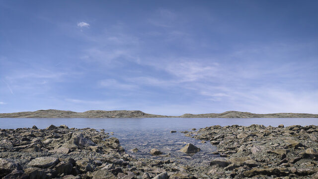 Peaceful lake scene in the afternoon with wispy clouds and blue sky reflecting in the still water. A calm, tranquil and serene, natural landscape.  