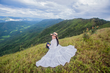 rear of happy woman wear white dress on top mountain looking view with mist and cloud at morning light Soft focus.