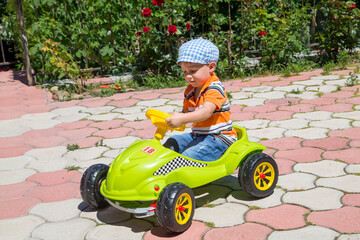 Happy boy drives a green children's car