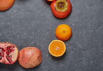 Orange, with grapefruit, pomegranate, passion fruit and kaki on dark background