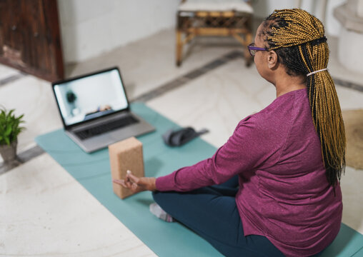 African Senior Woman Doing Yoga At Home With Laptop - Meditation, Mindfulness And Health Care