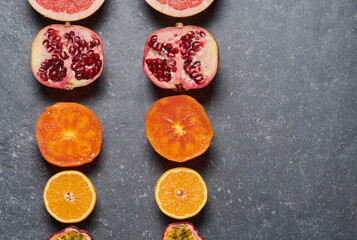 Lines of orange, grapefruit, pomegrade, passion fruit, kaki on grey background