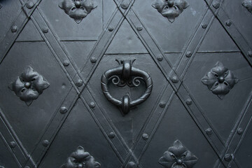 Wrought iron or steel knocker on riveted metal door in the Old Town of Warsaw