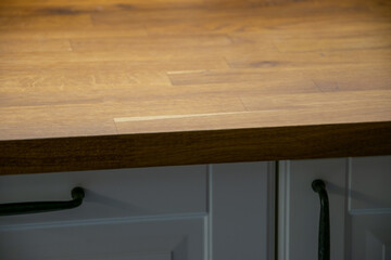 Rustic wooden oak kitchen countertop on cabinets with cream fronts and black handles