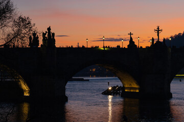 Obraz premium Silhouettes of people and statues on the Charles bridge in Prague, Czech Republic. Beautiful orange sky at sunset